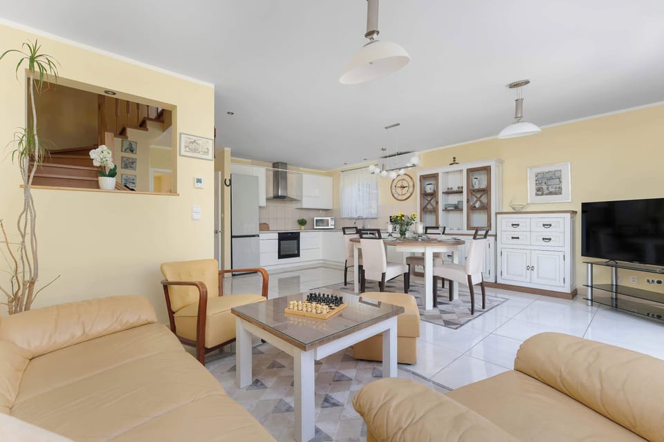 A combined kitchen and dining space with large windows and a bright, airy layout. Functional furnishings create a welcoming environment.