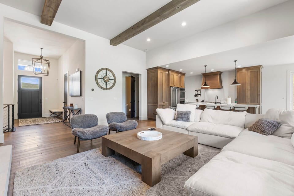 Picture yourself unwinding on the plush sectional, where exposed beams add rustic charm to this light-filled, open-concept living space that flows seamlessly into the gourmet kitchen.
