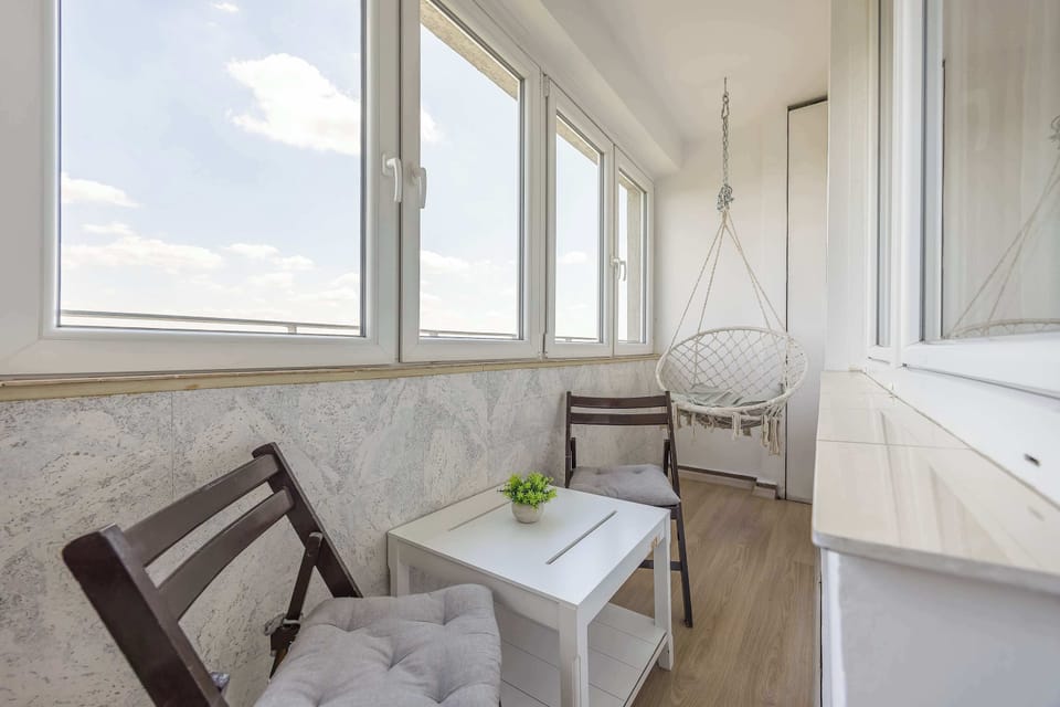 A cozy enclosed balcony with seating and beautiful city views. Relax with a cup of coffee while enjoying the skyline.