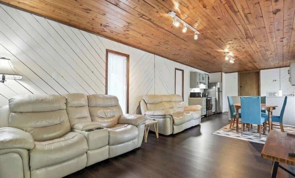 Stretch out, kick back, and enjoy the open-concept great room at Backbeat Bungalow. Featuring two plush reclining leather sofas, soaring wood ceilings, and a spacious layout connecting the living room, dining area, and kitchen, it's the perfect place