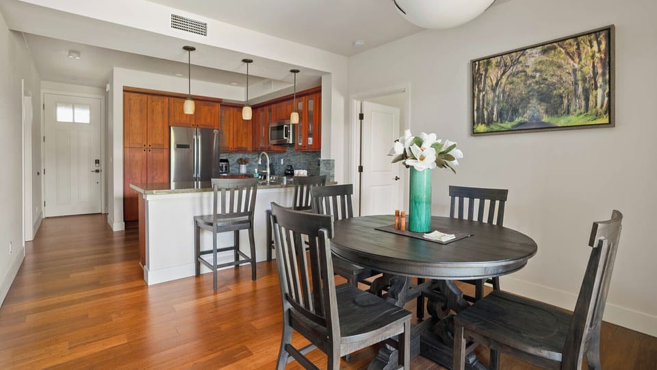 Gather around the spacious dining table, perfectly placed to connect with your fully equipped kitchen. Rich wood floors, warm pendant lights, and thoughtful touches create an inviting space where meals feel special.