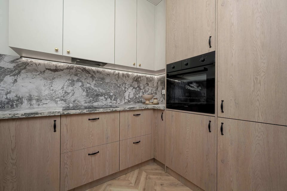 A comprehensive view of the kitchen cabinets displays the ample storage provided by the floor-to-ceiling wooden panels. The clean lines and handleless design contribute to the uncluttered look.