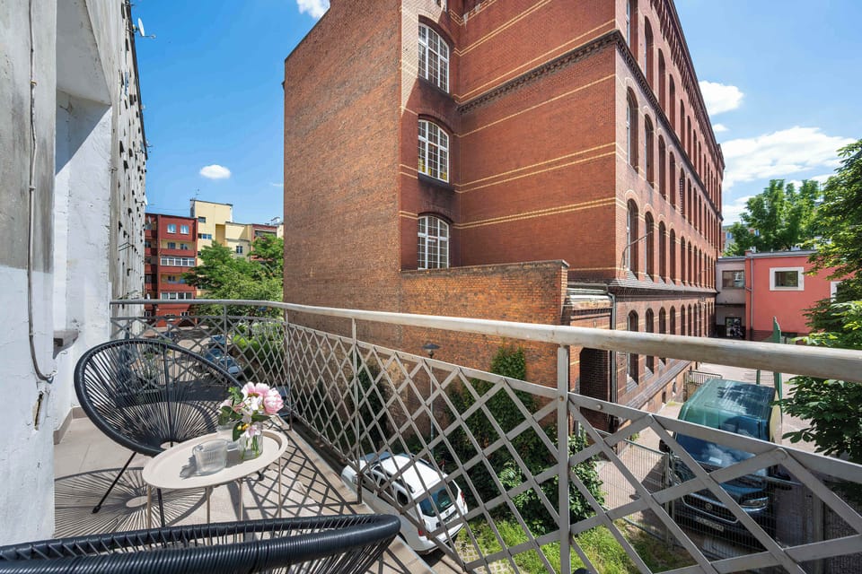 A different angle on the balcony highlights the contrast between the historic brick building opposite and the cozy seating area. It serves as an ideal spot to enjoy fresh air and sunshine.