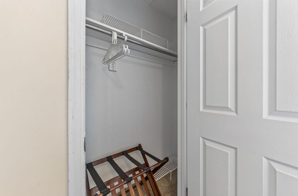 Bedroom closet with hanging space, extra hangers, an upper shelf, and a luggage rack.