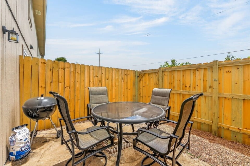 Private fenced patio with seating for four and a charcoal grill for relaxed outdoor meals.