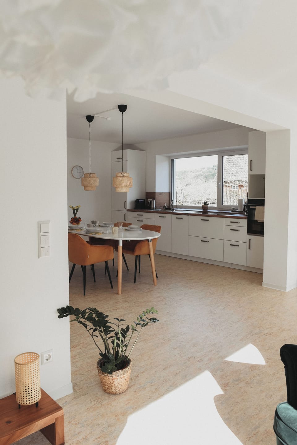 Sunlit modern kitchen with big window, sleek cabinets, cozy dining nook.