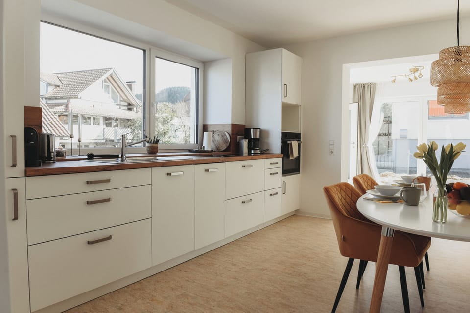 Sunlit modern kitchen with dining nook, coffee bar, and terrace views.