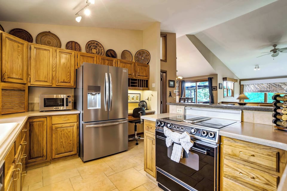 Stainless steel appliances pair with warm oak cabinetry and tile floors, creating a functional, well-appointed kitchen ready for everything from quick breakfasts to full dinners.
