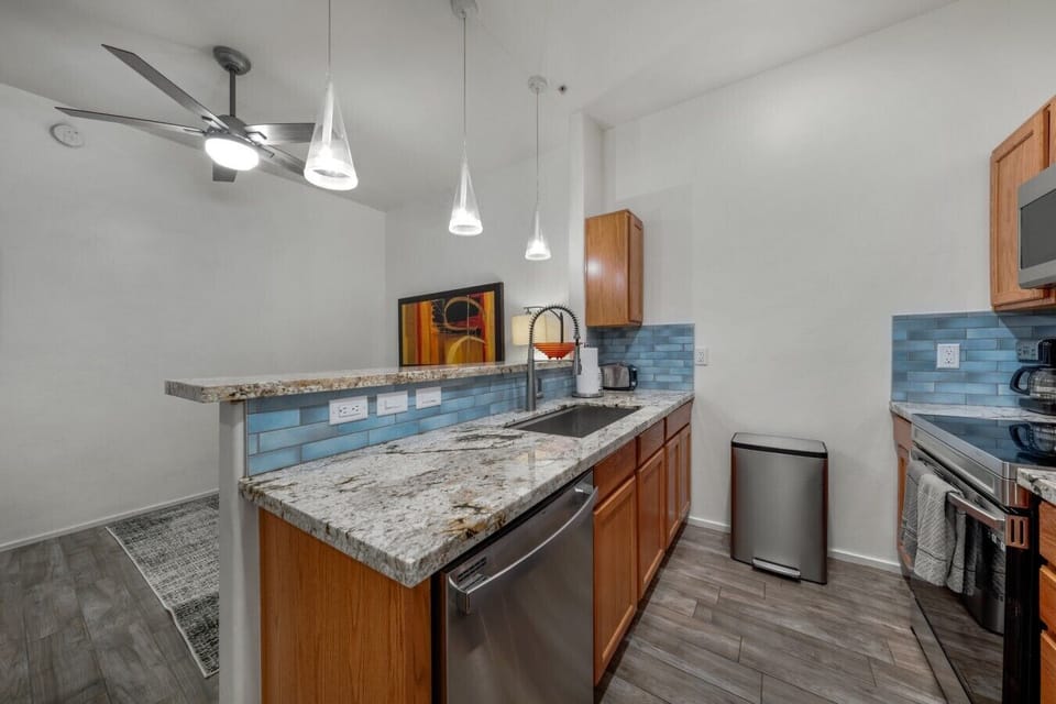 Bright galley layout with deep granite sink, dishwasher, and stylish pendant lighting overhead