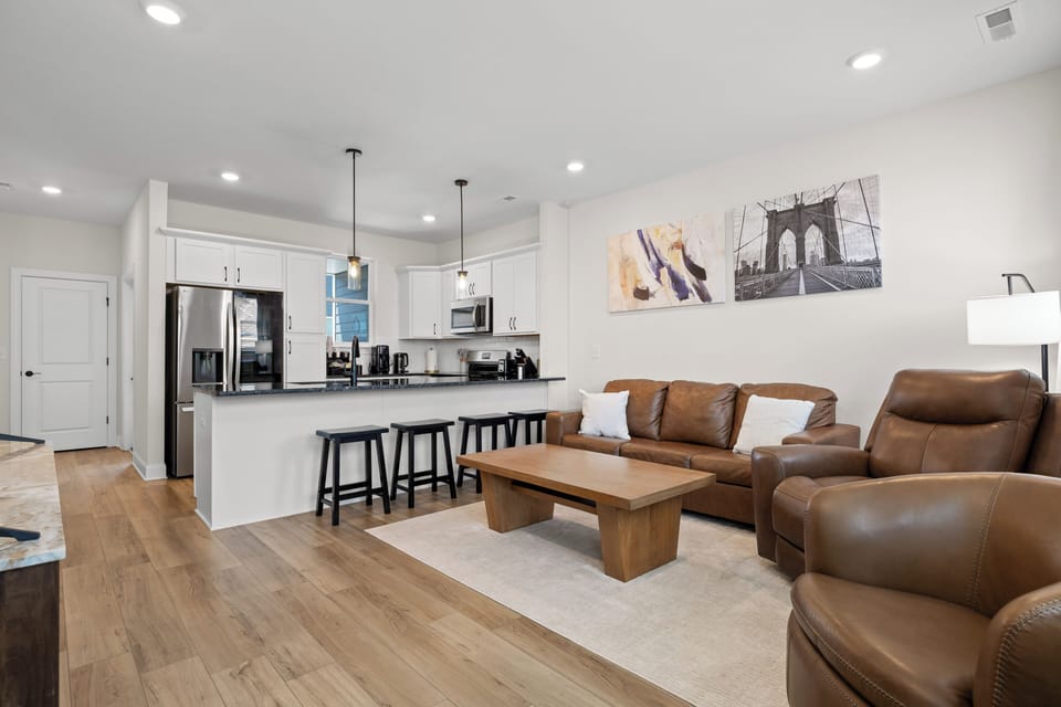 Bright open-concept living room and kitchen with leather seating