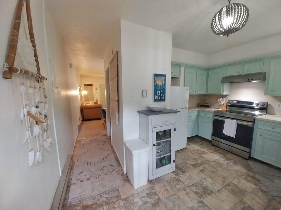 Your fully equipped kitchen with charming mint cabinets, modern appliances, and coastal décor awaits—perfect for preparing meals together after a day of adventure.
