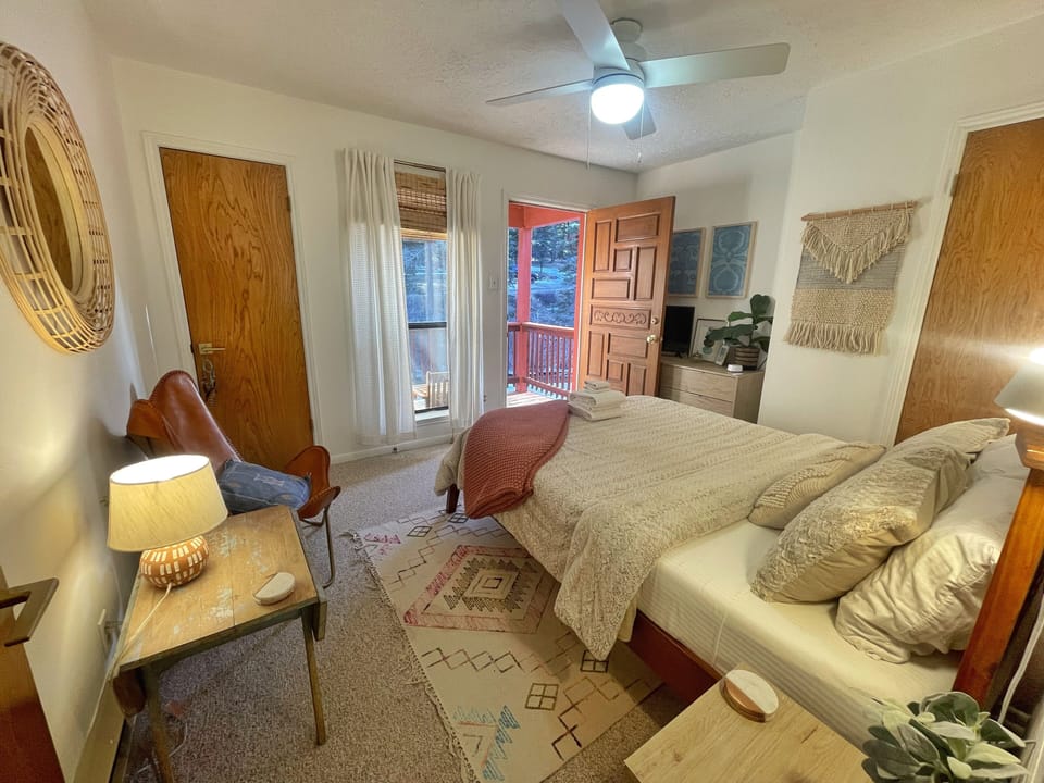 Unwind in your cozy bedroom with warm wood tones, soft textiles, and a peaceful view. French doors open to your private deck, inviting fresh mountain air in.