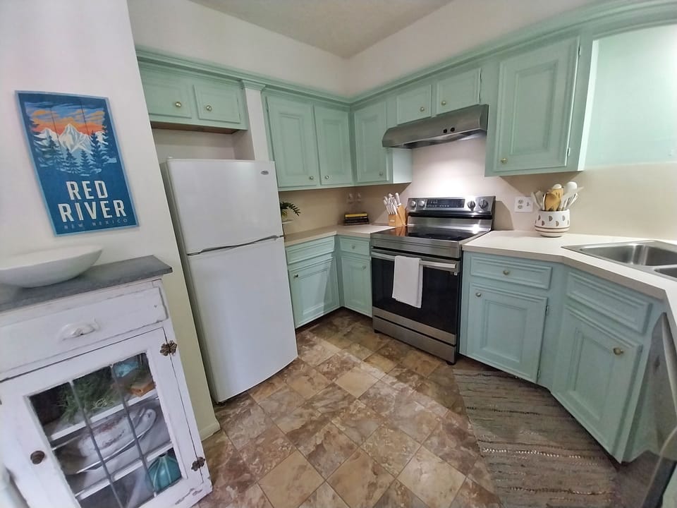 A fully equipped kitchen with charming mint-green cabinetry and modern appliances awaits your culinary adventures. Everything you need to cook, dine, and feel at home during your mountain getaway.