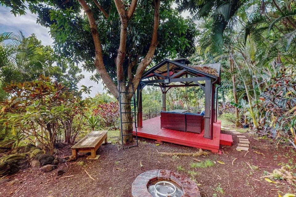 Garden bench offers shaded seating beneath tropical trees and foliage