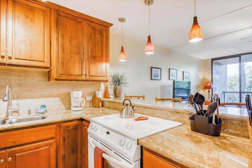 Functional kitchen cooking space featuring a white stove, rich wood cabinets, smooth countertops, and overhead pendant lighting! 🍳💡