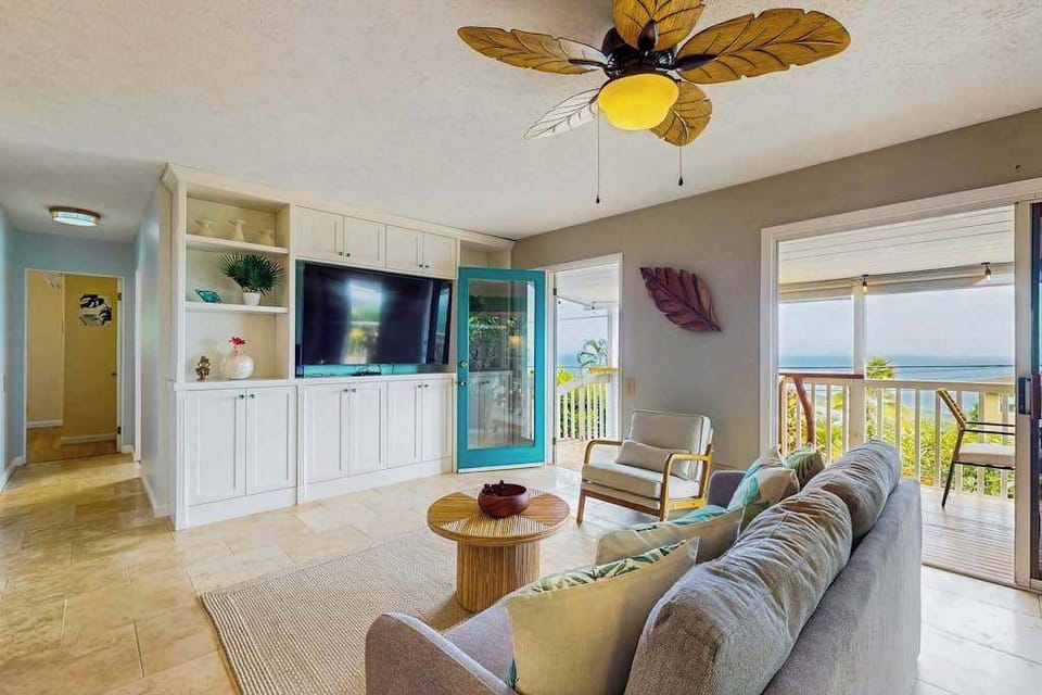 Living room seating faces windows with tropical scenery and breezes