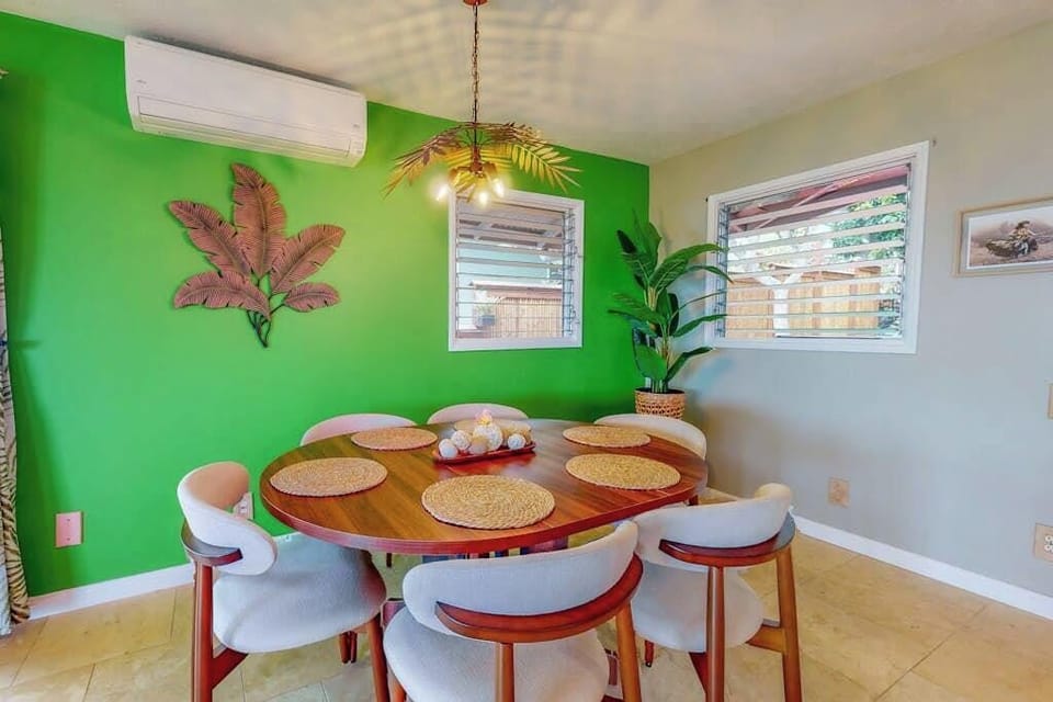 Green dining area offers cheerful seating beneath playful tropical artwork