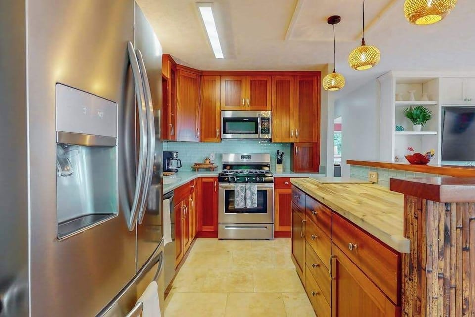 Warm kitchen features wood cabinetry modern appliances and ample counters