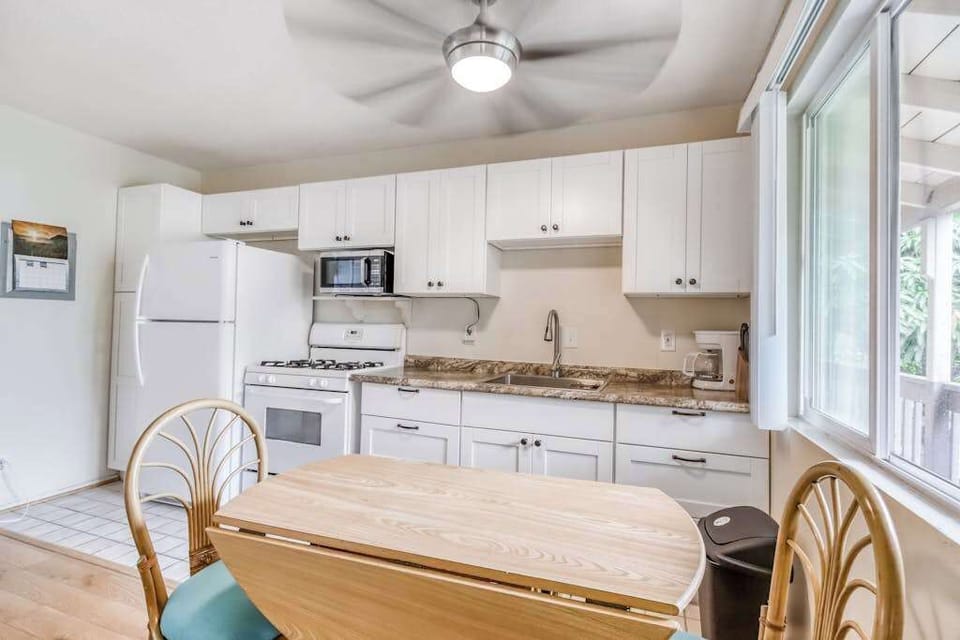 Fully Equipped Kitchen with White Cabinetry & Small Dining Table Setup
