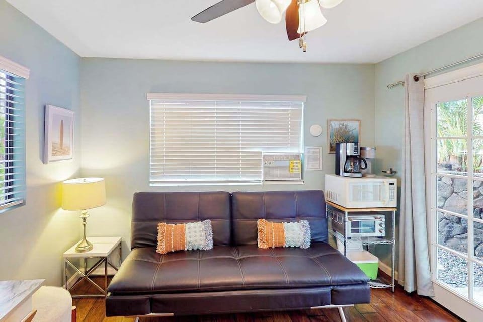Cozy secondary living room equipped with a convertible sofa, cooling ceiling fan, and a convenient coffee and microwave station! 🛋️✨