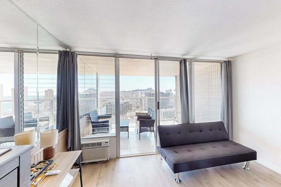 Convertible futon sofa positioned adjacent to floor-to-ceiling sliding glass doors, seamlessly blending indoor living with the private balcony.