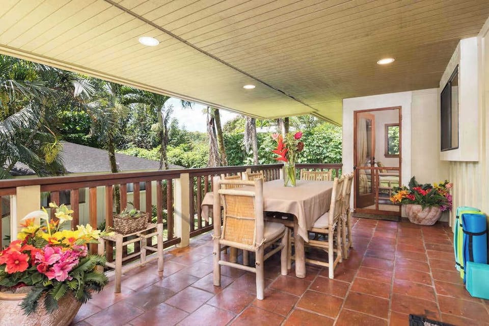 Covered dining patio provides colorful seating beside tropical garden surroundings
