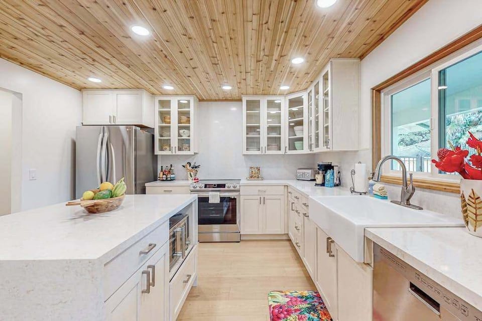 Bright kitchen showcases white cabinetry island seating and garden windows