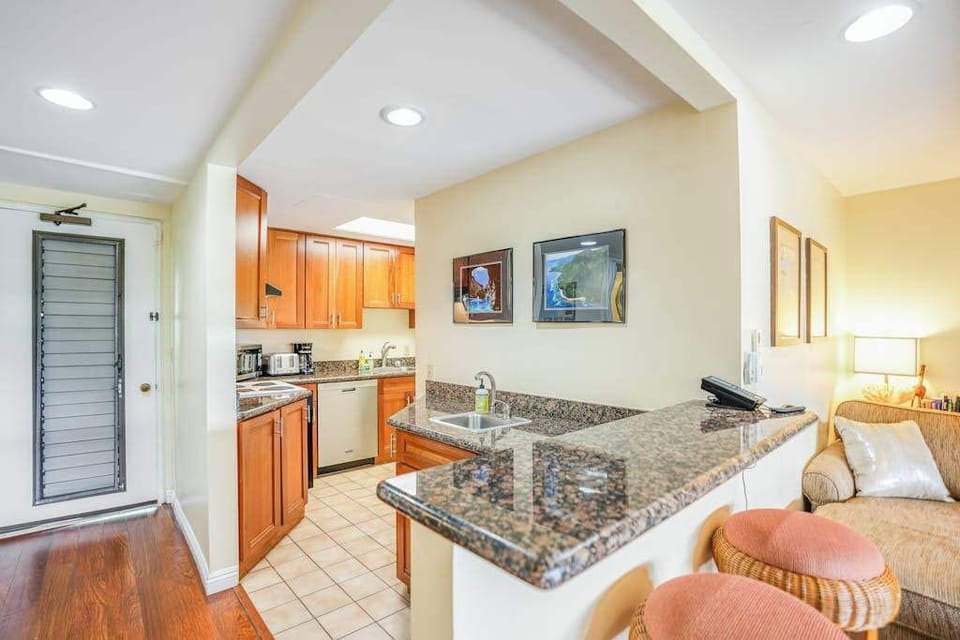 Modern kitchen features granite countertops, bar seating, and ample cabinetry