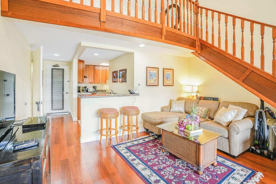 Spacious living room showcases hardwood floors, staircase, and inviting seating