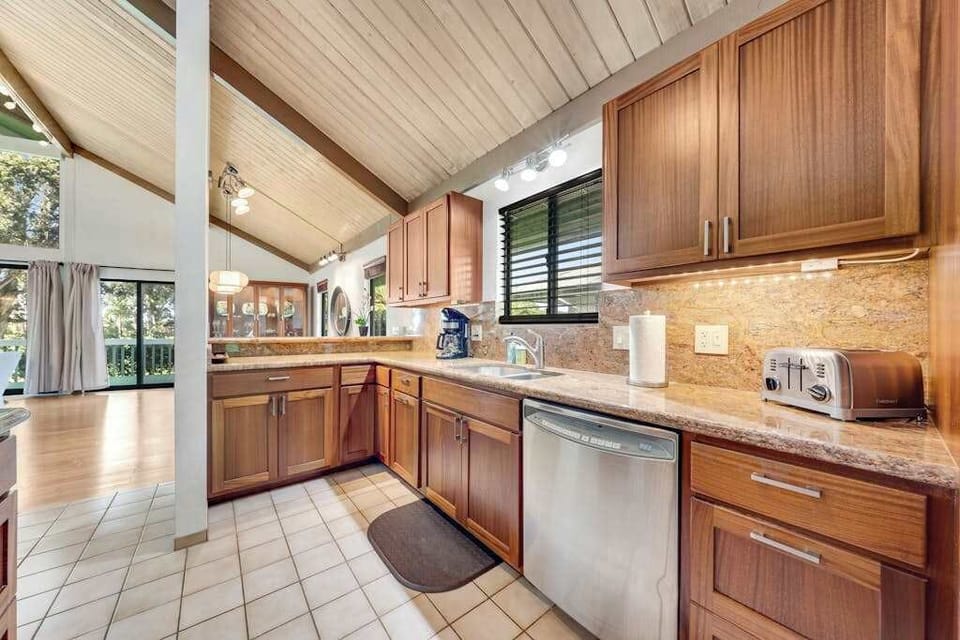 Vaulted kitchen gleams with wooden cabinets dishwasher and generous counters