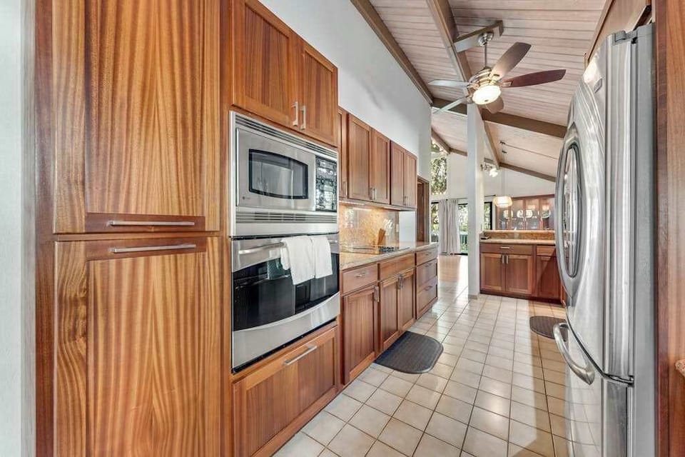 Stainless appliances complement timber cabinets beneath vaulted ceiling and skylight