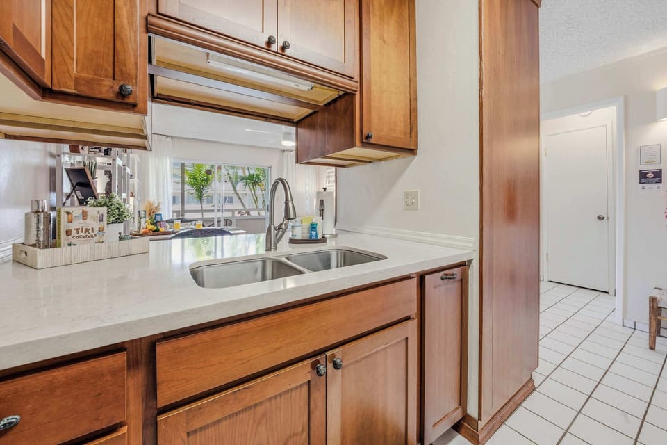 Kitchen setup with double stainless steel sink, wooden cabinets & white countertops