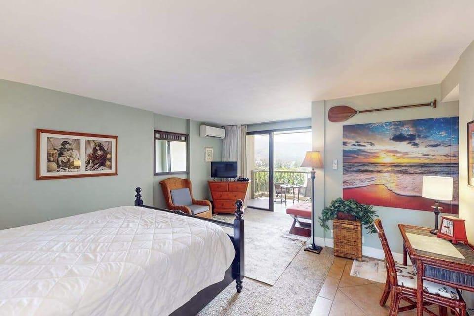 Bright studio includes comfortable bedding, dresser, artwork, and peaceful decor