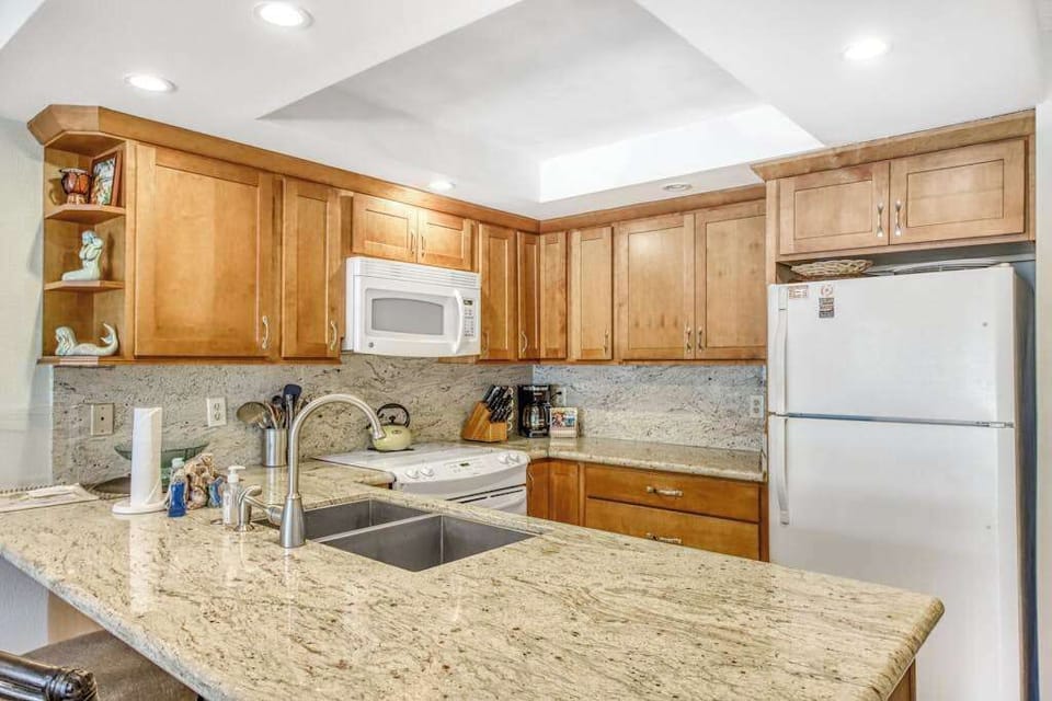 Kitchen island offers generous workspace beside stools and bright cabinetry