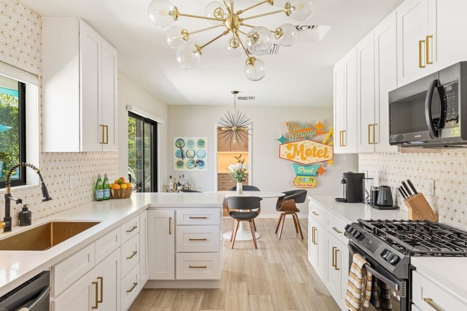 Fully stocked kitchen with brass fixtures, gas range, and playful neon accents.