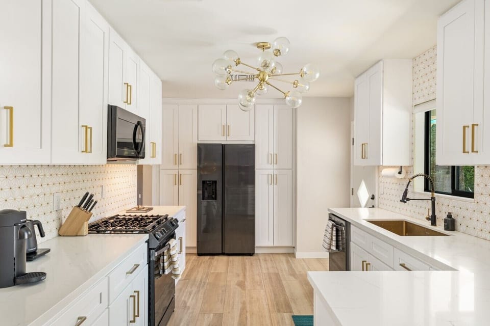 Fully equipped chef`s kitchen with black stainless appliances and brass finishes.