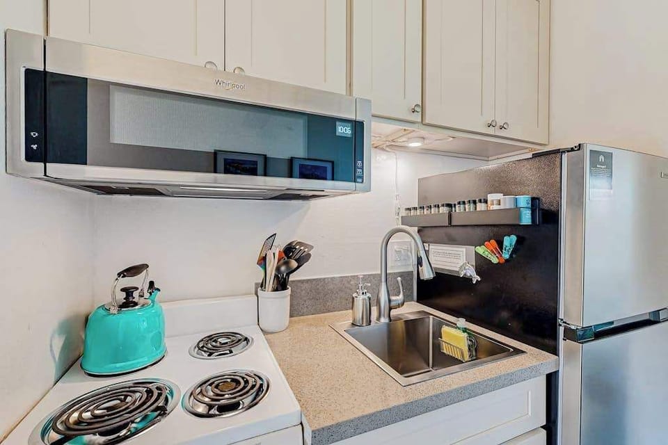 Kitchen area with a Whirlpool over-the-range microwave and a light blue kettle 
