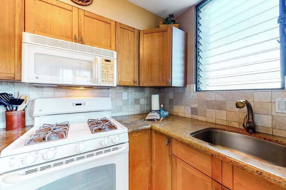 Fully Equipped Kitchen with Gas Stove, Overhead Microwave, and Tile Backsplash