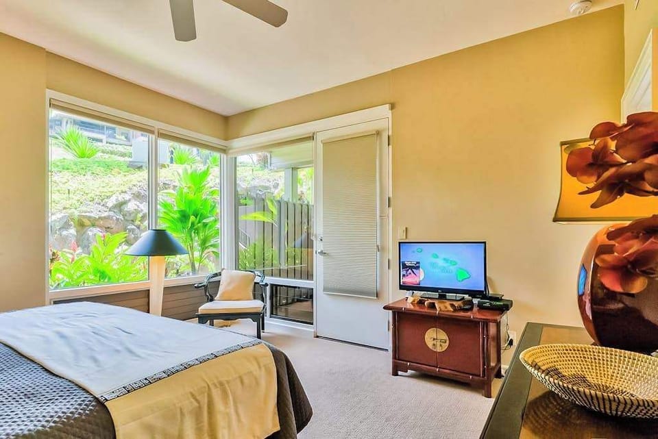 Master bedroom with king bed, flat screen tv and large windows for tropical views and private lanai access.