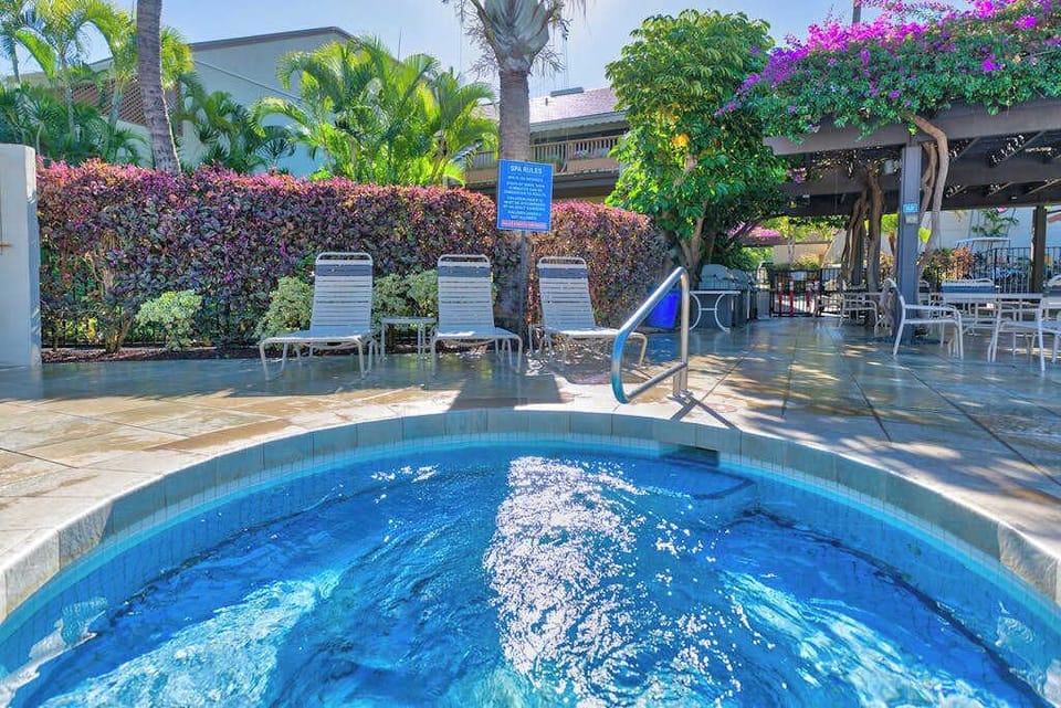 Resort pool sparkles beside tropical foliage, flowering shrubs, and loungers