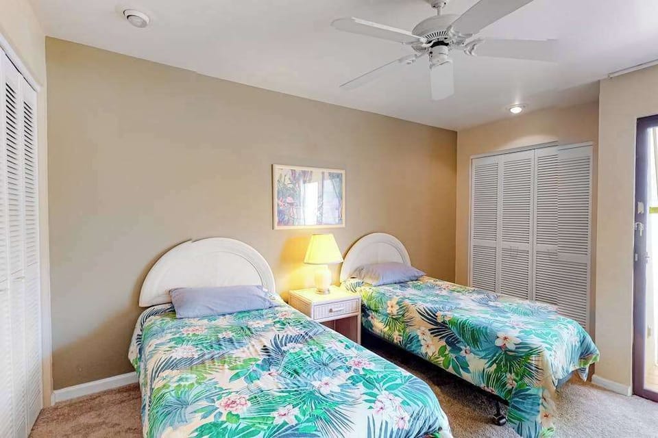 This bedroom features twin beds ceiling fan and natural light