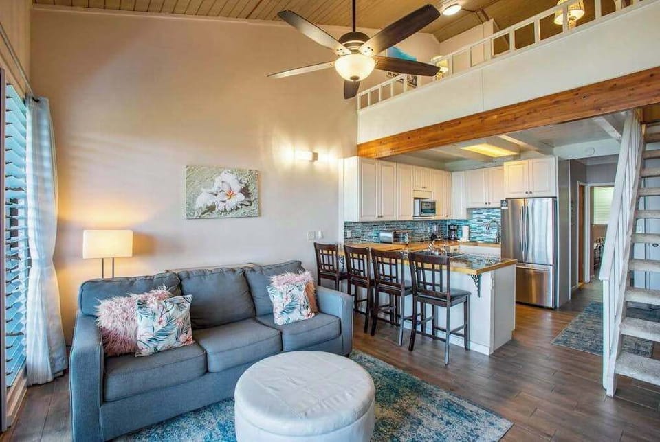 Living room with flat screen tv, sleeper sofa and rays of light streaming in from the lanai.