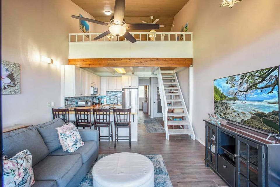 Living room with flat screen tv, sleeper sofa and rays of light streaming in from the lanai.