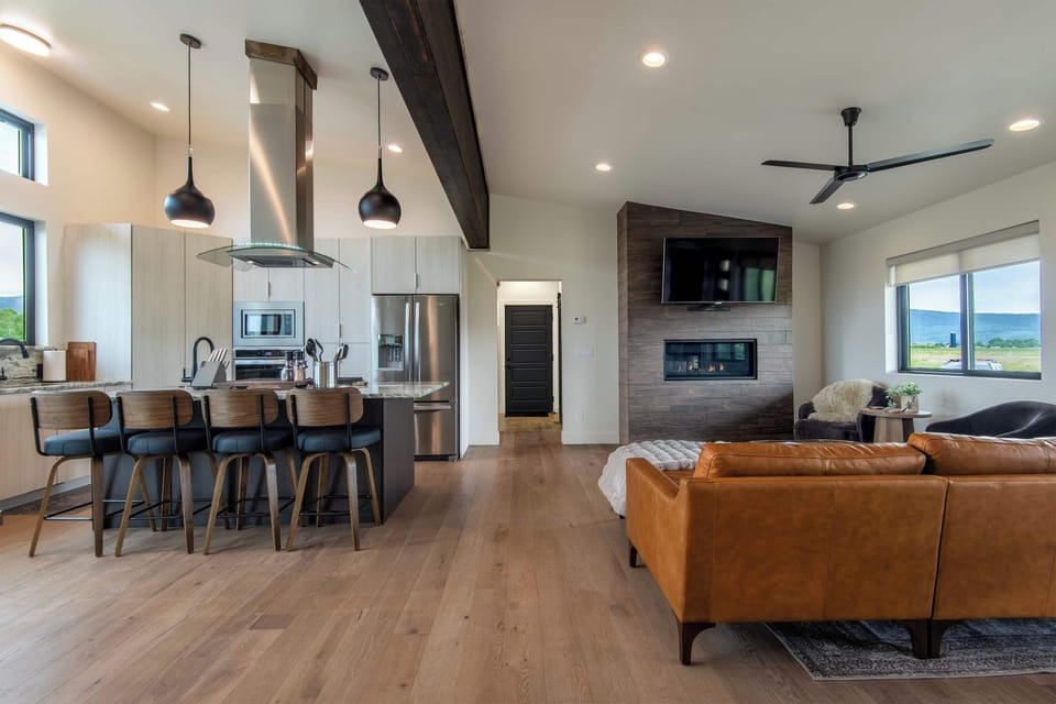 The open great room stretches from kitchen to living in one unbroken flow of light, wood, and mountain views — built for groups who want to be together.