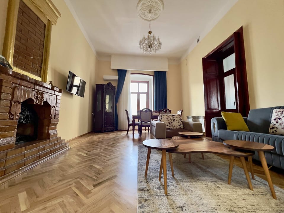 Second living-room view with high ceilings, dining space and a decorative inactive fireplace.