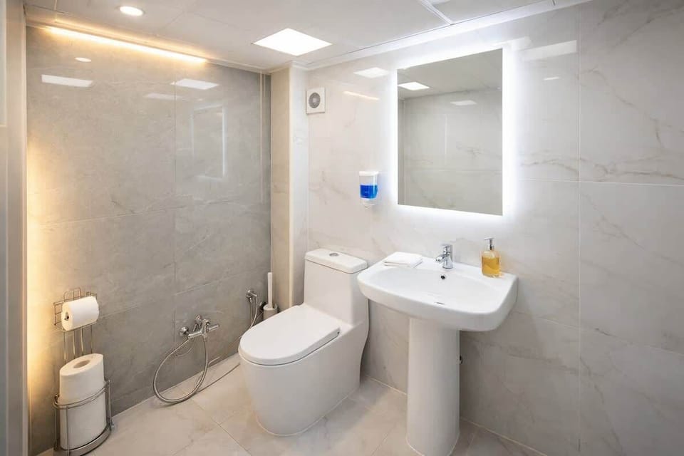 Bright, modern bath with LED mirror, walk-in shower, and bidet spray.