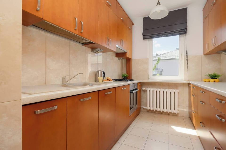 A fully equipped kitchen with wooden cabinets and a large countertop. A window provides plenty of natural light.