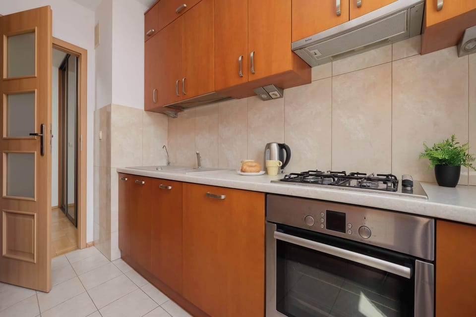 A functional kitchen with a gas stove, oven, and sink. Wooden cabinets offer plenty of storage space.
