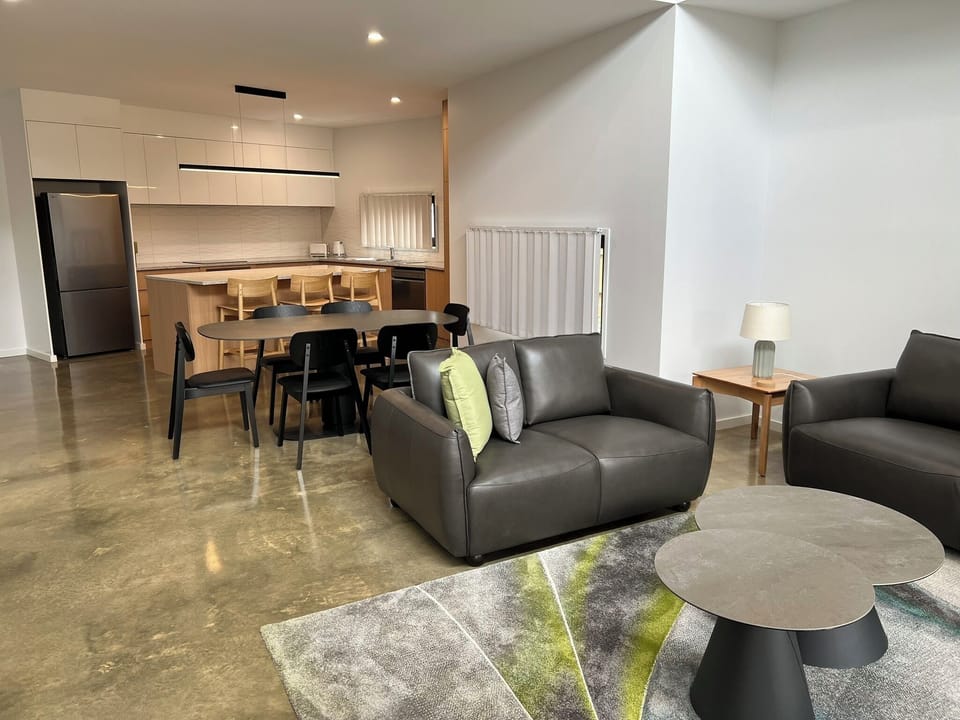 Open-plan living with sleek kitchen, leather sofas & polished floors