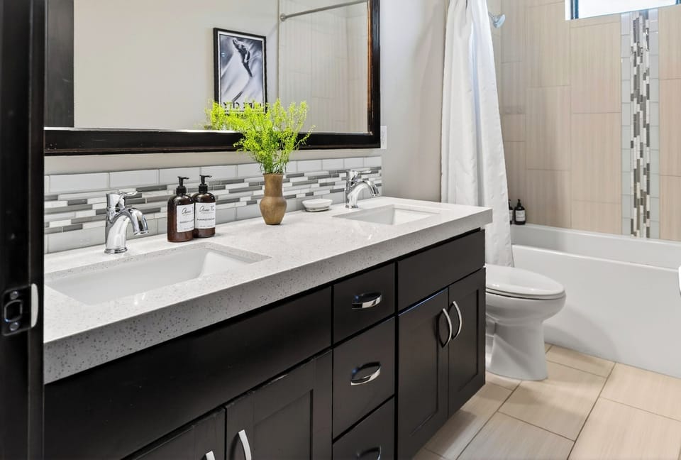 Sleek dark-stained cabinetry paired with a dual basin sink and custom tile borders.